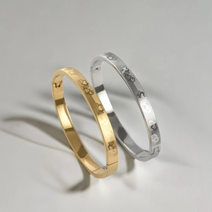 Macro shot of gold and silver titanium bracelets with heart engraving and mesh texture