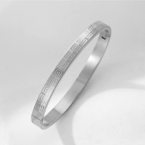 Macro view of silver titanium steel bangle showing detailed geometric greek key patterns
