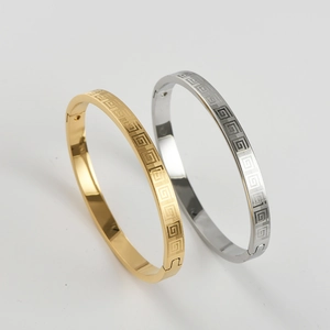 Detail showing gold and silver titanium steel bracelets with engraved Greek key patterns