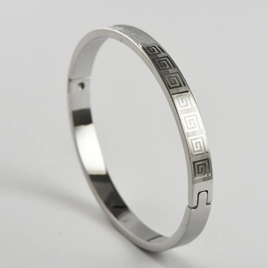 Detailed view of silver stainless steel bangle with Greek key pattern and hinge closure