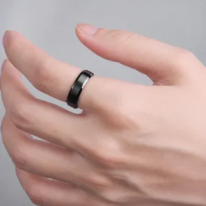 Primer plano de un anillo minimalista de titanio negro mate con diseño tallado en la mano