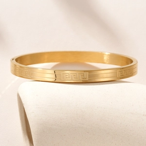Polished gold titanium steel bangle featuring Greek meander engraving with clasp