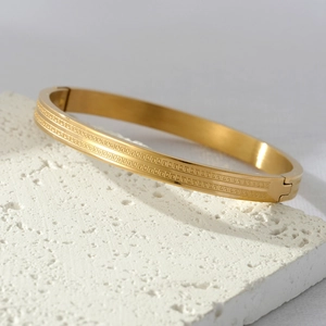 Gold titanium steel cuff bracelet featuring dual Greek key patterns and secure hinge clasp
