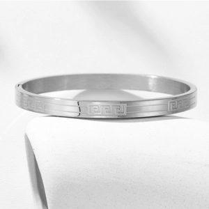 Macro detail of silver stainless steel bracelet featuring engraved Greek meander patterns