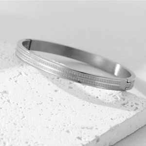 Detailed close-up of a silver titanium steel bangle featuring a double Greek key pattern