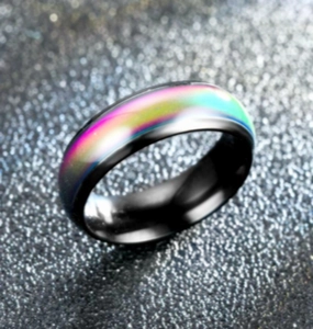 Gros plan d'une bague noire en acier inoxydable thermochrome sur fond sombre scintillant