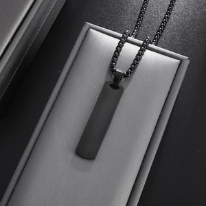 Detalle de collar con colgante rectangular negro sobre estuche de joyería gris cepillado
