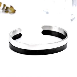Detail view of a minimalist C-shaped stainless steel bracelet with silver and black finish