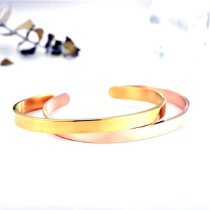 Polished gold and rose gold C-shape stainless steel open bangles on white background