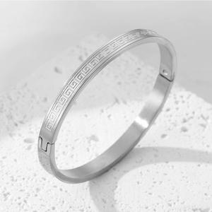 Detailed macro view of silver titanium steel bangle featuring a Greek meander pattern
