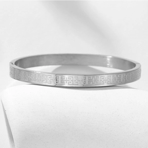 Silver stainless steel bangle with engraved geometric Greek fret pattern texture