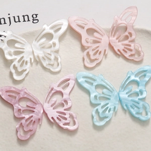 Detailed view of hollow acetate butterfly charms with pearlescent iridescent texture