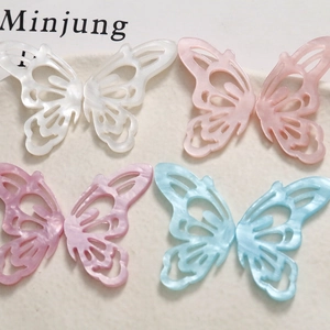 Macro detail of hollow acetate butterfly charms with pearlescent finish in four colors