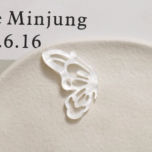 Detailed view of a white hollow butterfly charm with pearl luster for DIY hair accessories