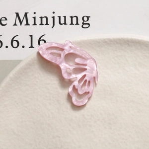 Macro shot of pink acetate butterfly accessory with marble texture and cutout detail