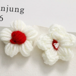 Detailed view of handmade crochet puff flowers with white petals and red centers