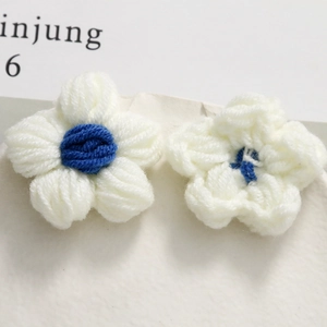 Macro detail of handmade crochet puff flower accessories in soft cream and navy blue yarn