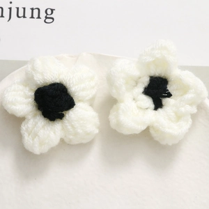 Macro shot of handmade crochet puff flowers in black and white on a ceramic tray
