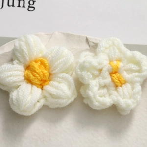 Detailed close-up of handmade crochet flowers in white and yellow yarn with soft texture