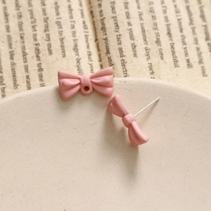 Detail of pink bow earrings with matte finish and S925 silver needles on stone tray