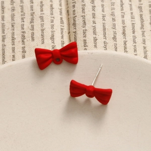 Detail view of red bow earrings with matte finish showing front and stud back structure