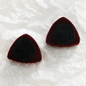 Detalle del clip de pelo rojo aterciopelado con rosa negra y estilo vintage retro