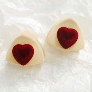 Detalle de pinzas de pelo triangulares beige con adorno de corazón rojo terciopelo
