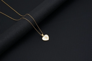 Golden heart necklace with shell inlay and cursive letter B on a black background