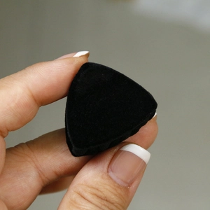 Primer plano de una pequeña pinza de pelo triangular negra con textura de terciopelo