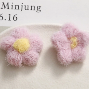 Macro view of handmade pink knit flower charms with yellow centers for DIY accessories