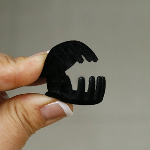 Primer plano de una mini pinza de pelo negra flocada sostenida entre los dedos para niños