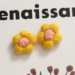 Dettaglio di piccoli fiori all'uncinetto gialli con cuore rosa per gioielli fai-da-te