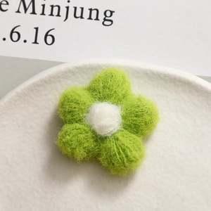 Macro view of handmade green felt flower accessory with soft wool texture and white stamen