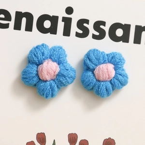 Dettaglio di due fiori all'uncinetto fatti a mano blu e rosa per accessori fai da te