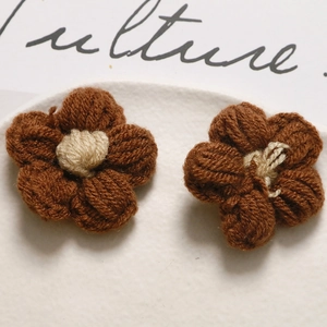 Macro detail of two handcrafted crochet flower accessories in brown and cream yarn