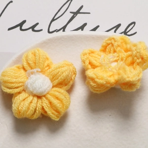 Close-up of handmade crochet puff flowers in yellow and white on a ceramic plate