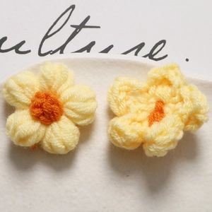 Macro shot of yellow and orange handmade crochet puff flowers in a white ceramic dish