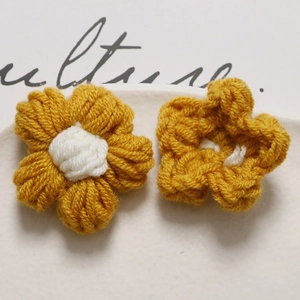 Detail of handmade crochet puff flowers in yellow and white yarn for DIY accessories