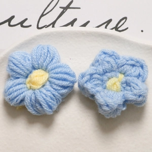 Detailed macro view of two handmade blue crochet flowers on white ceramic plate