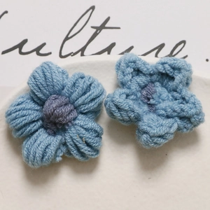 Macro detail of handmade crochet puffy flower charms with purple knit texture for DIY jewelry