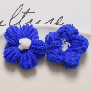 Close-up of two handmade blue crochet puff flowers with white centers for DIY accessories