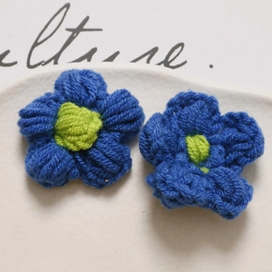 Close-up of handmade crochet puff flower in dark blue and neon green yarn for DIY