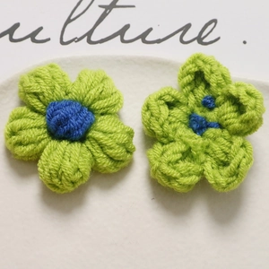 Macro shot of handmade crochet puff flowers in vibrant green and blue for DIY hair accessories