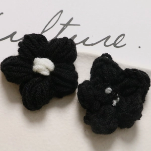 Close-up of handmade black crochet puff flowers with white centers for DIY accessories