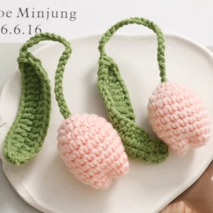Close-up of pink knitted tulip keychain with green leaves and soft cotton texture