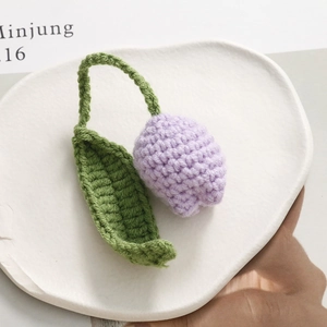 Detail of handcrafted crochet purple tulip charm with green leaf for bags and keys