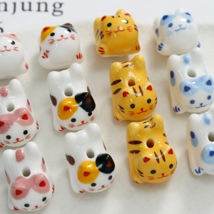 Close-up of handmade cartoon ceramic cat beads with holes for DIY jewelry making