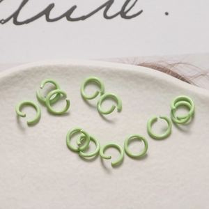 Dettaglio macro di anellini aperti verde menta opaco per gioielli fai-da-te su ceramica