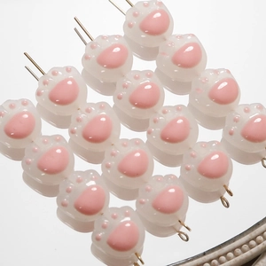 Detalle macro de cuentas de pata de gato para joyería DIY en rosa suave y blanco
