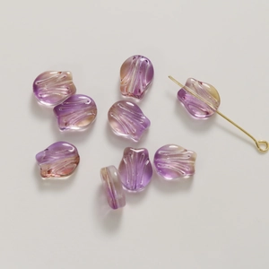 Macro detail of tulip glass beads with purple gradient and gold glitter for DIY crafts